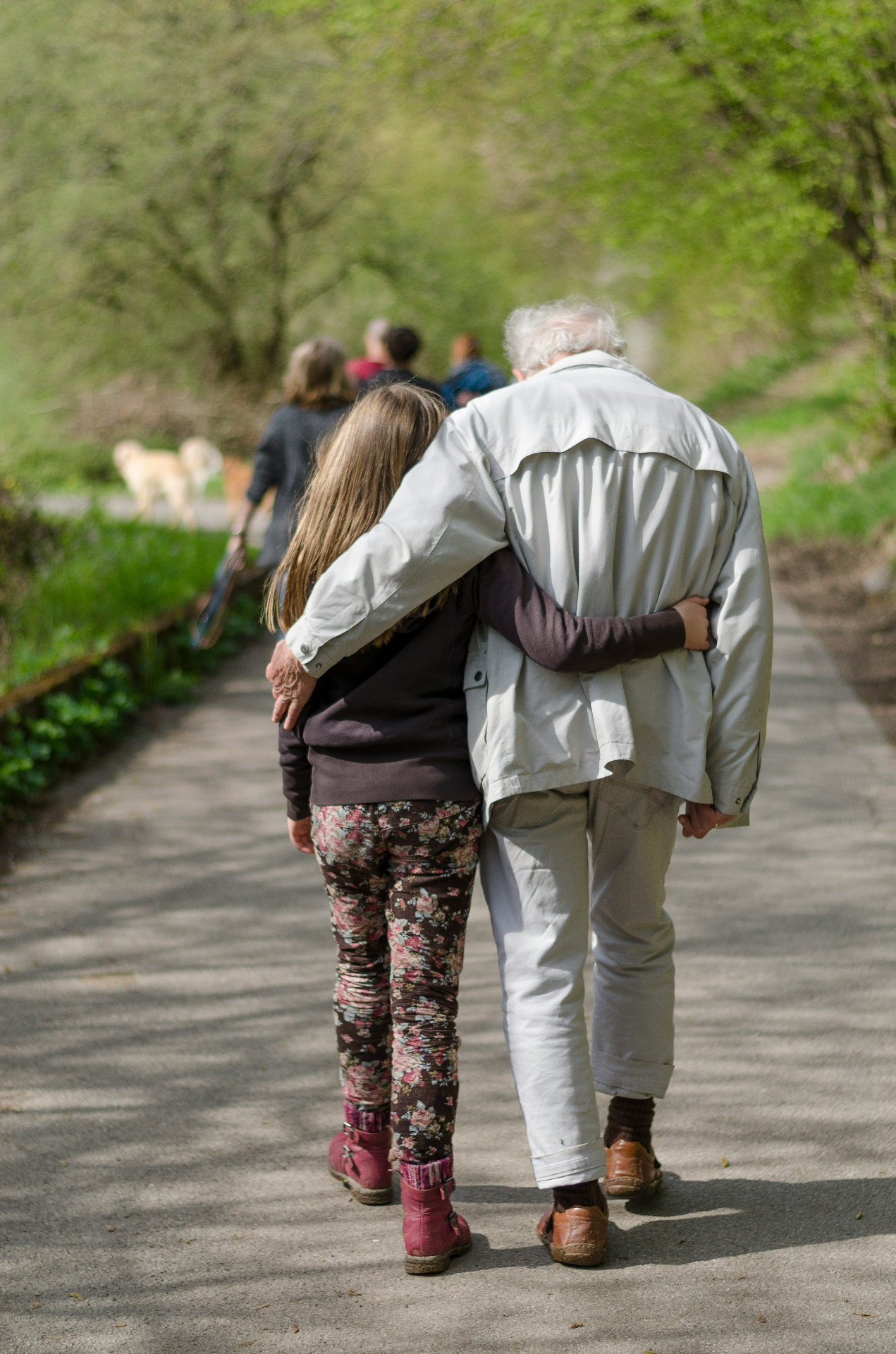 Grandfather walking with his granddaughter, arms around each other