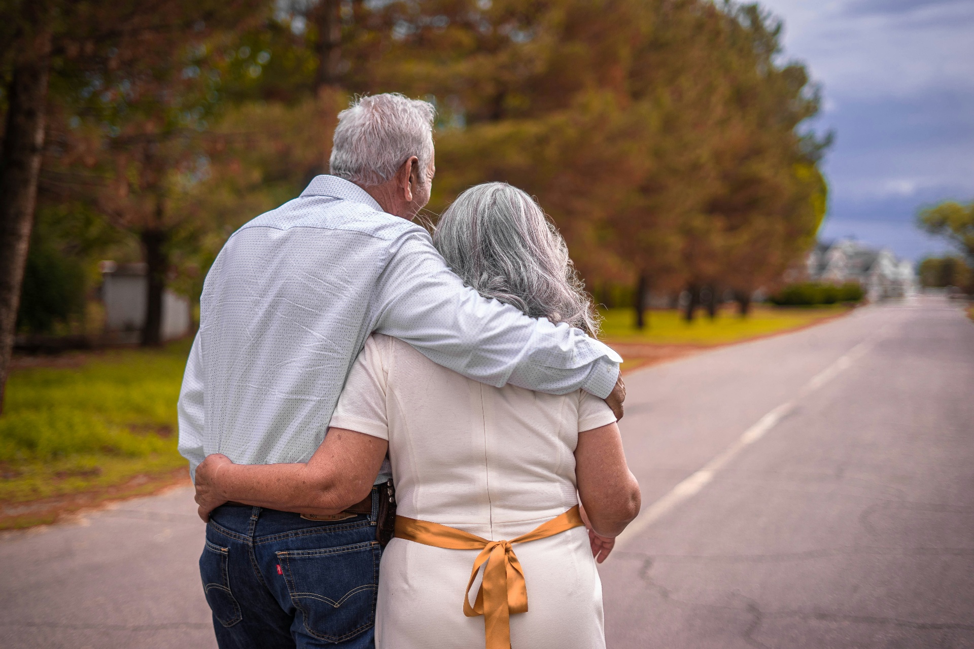 Senior couple walking arm-in-arm down a quiet road