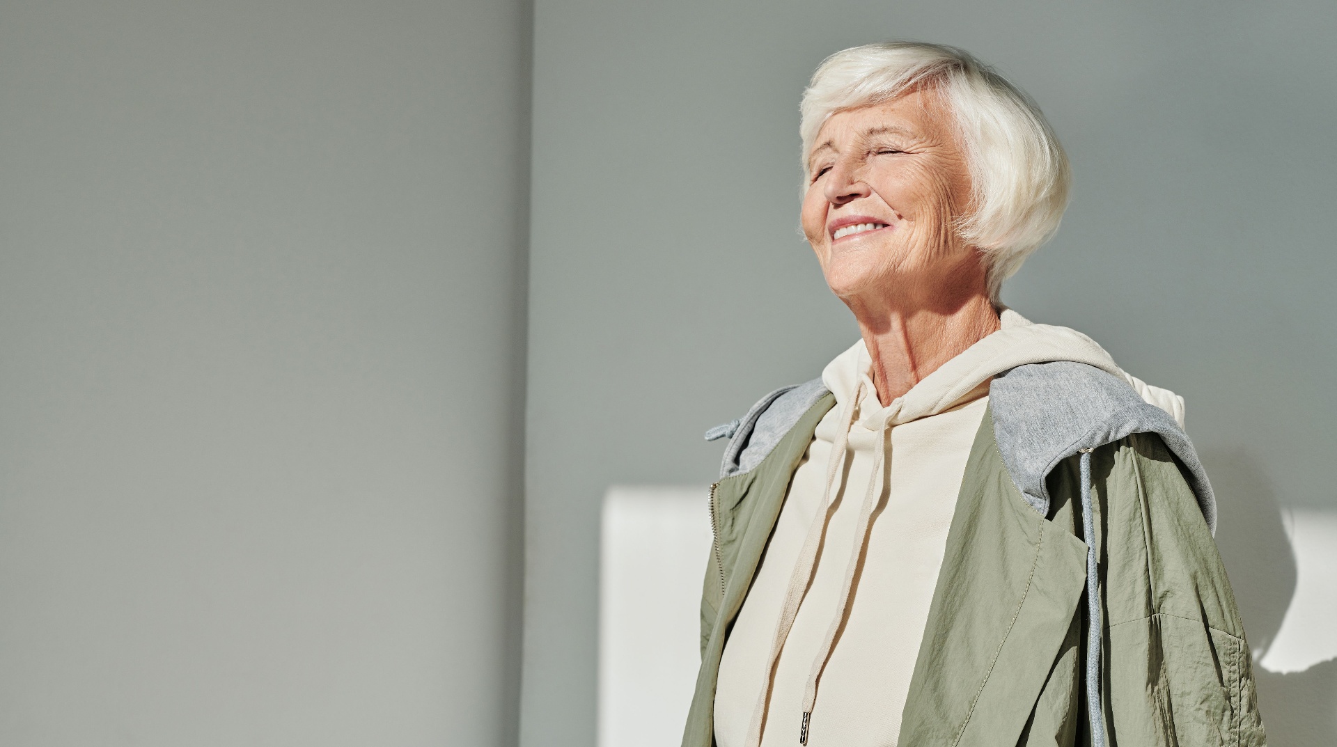Smiling senior woman standing in warm sunlight